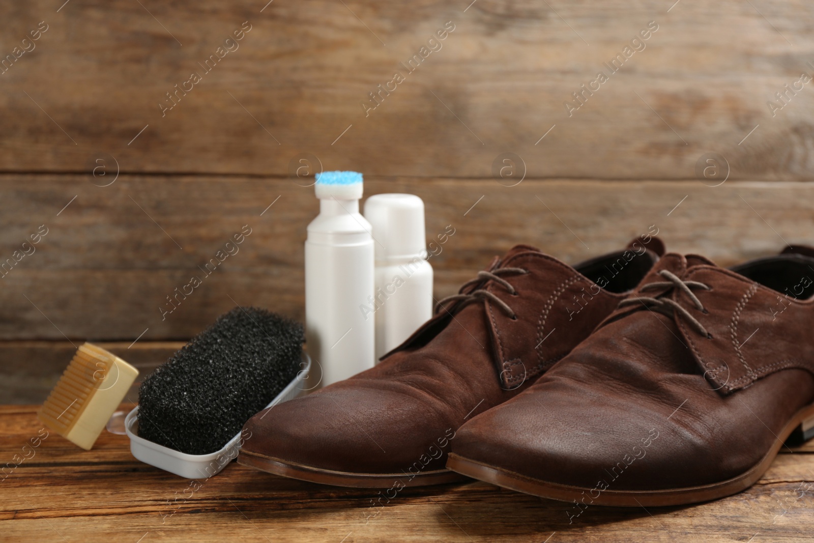 Photo of Stylish footwear with shoe care accessories on wooden table