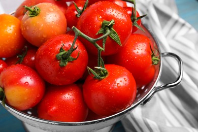 Many different ripe tomatoes in colander on table, closeup