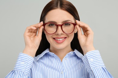 Photo of Portrait of smiling woman in stylish eyeglasses on grey background