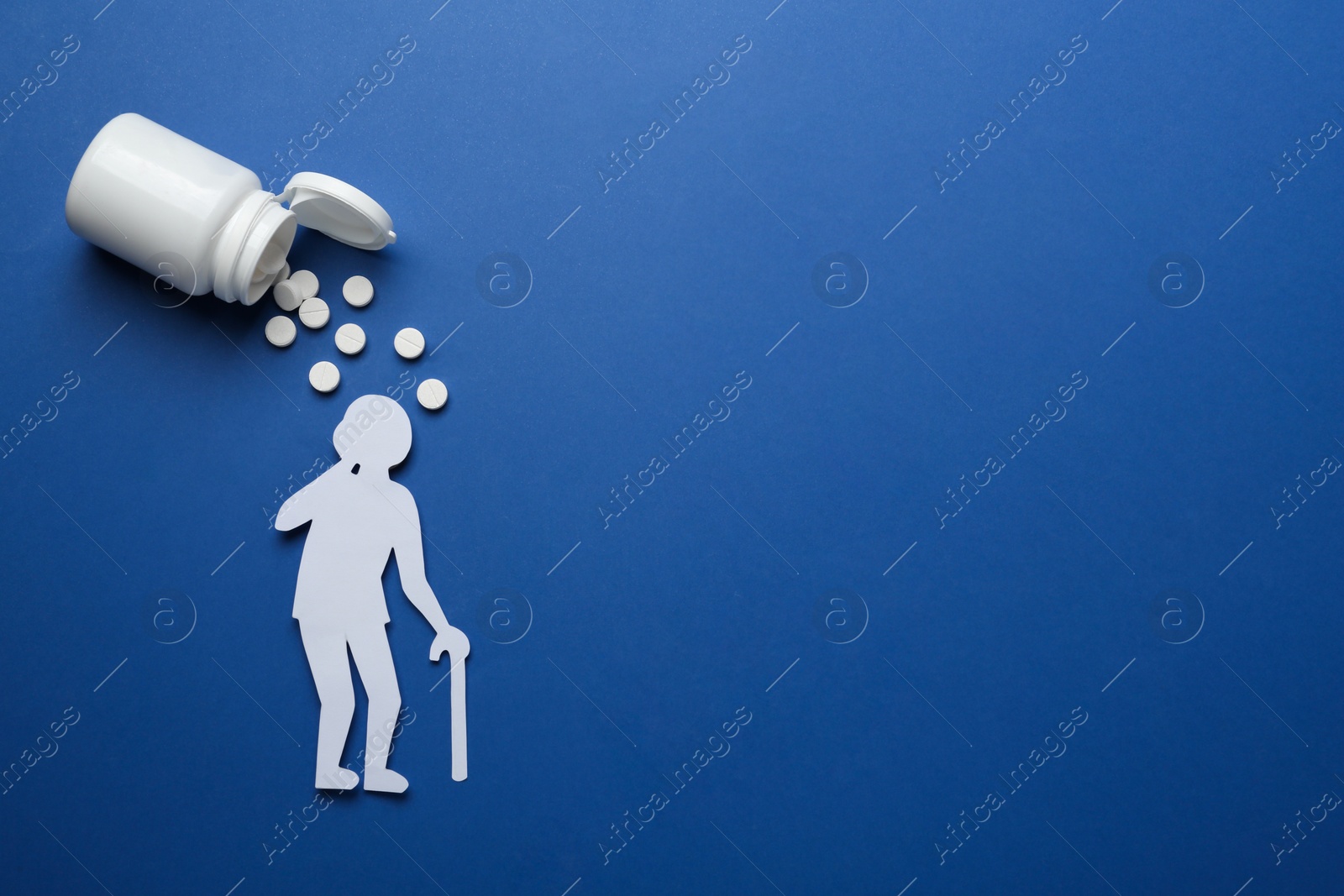 Photo of Old person paper cutout and pills on blue background, flat lay with space for text. Dementia concept