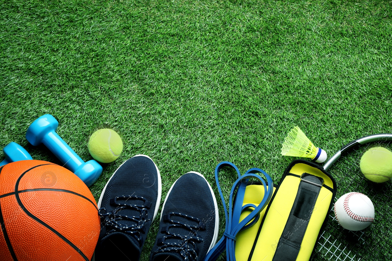 Photo of Set of different colorful sports equipment on green grass, flat lay. Space for text