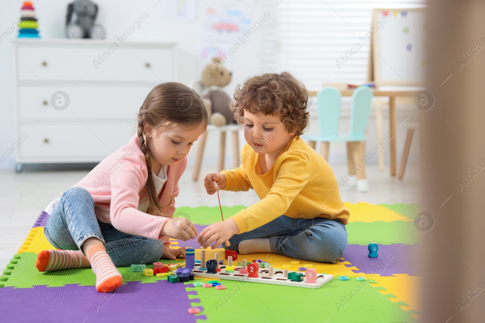 Photo of Cute little children playing with math game Fishing for Numbers on puzzle mat in kindergarten