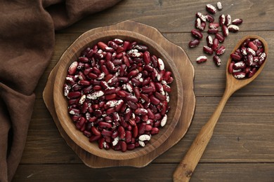 Bowl and spoon with dry kidney beans on wooden table, flat lay