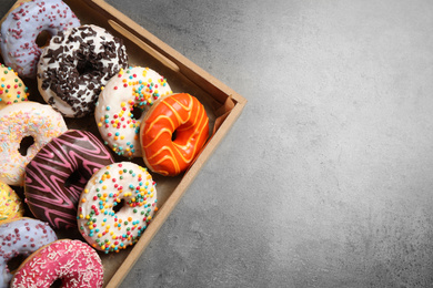 Photo of Top view of yummy donuts with sprinkles in box, space for text