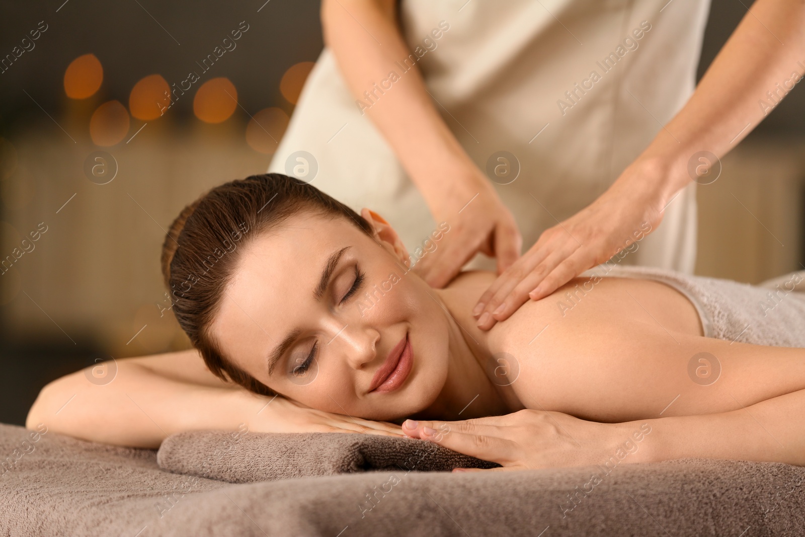 Photo of Beautiful young woman enjoying massage in spa salon