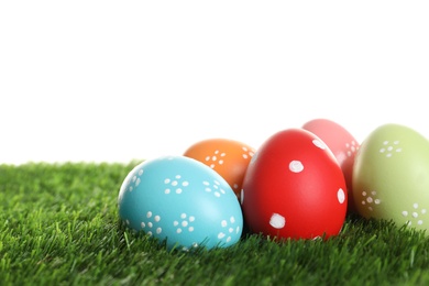 Photo of Colorful painted Easter eggs on green grass against white background