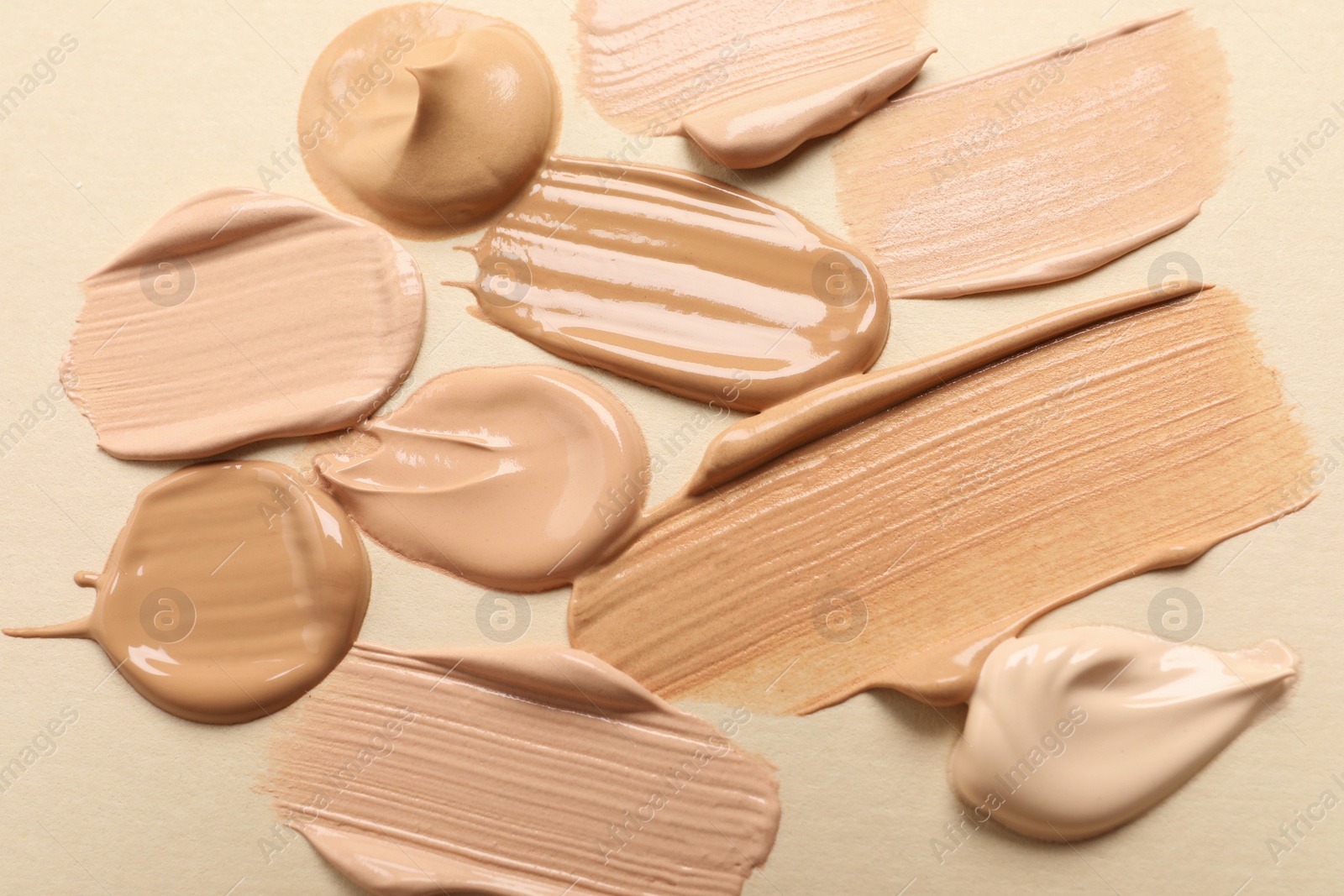 Photo of Samples of skin foundation on beige background, closeup