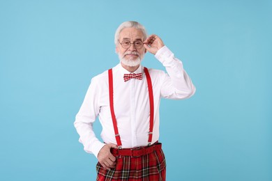 Photo of Portrait of stylish grandpa with glasses and bowtie on light blue background