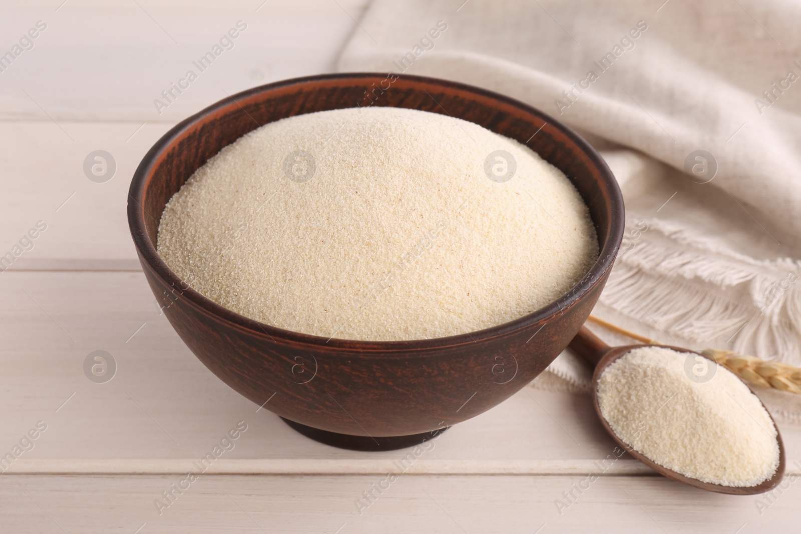 Photo of Uncooked organic semolina on white wooden table