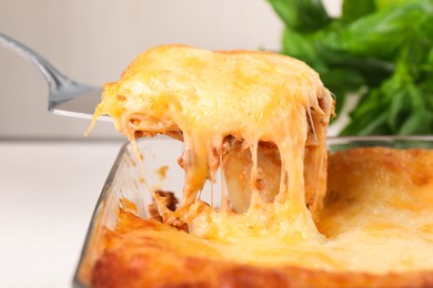 Photo of Taking piece of delicious lasagna from baking dish, closeup