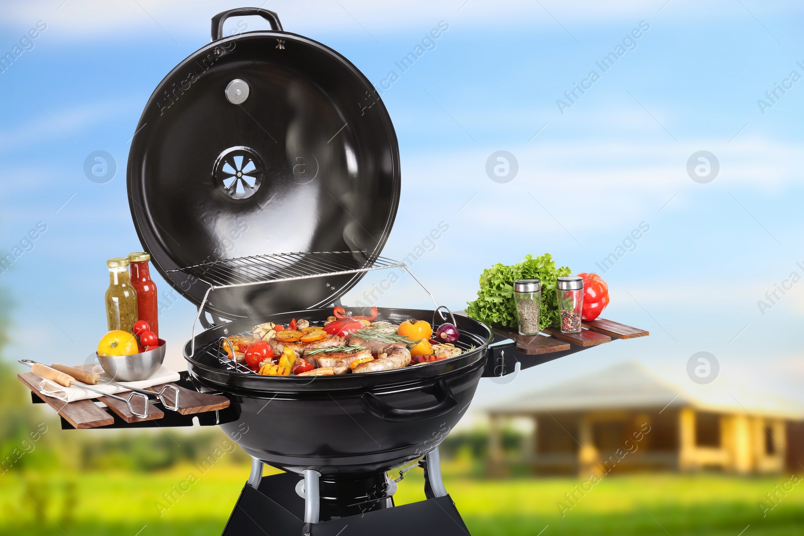 Image of Barbecue grill with meat products and vegetables outdoors on sunny day