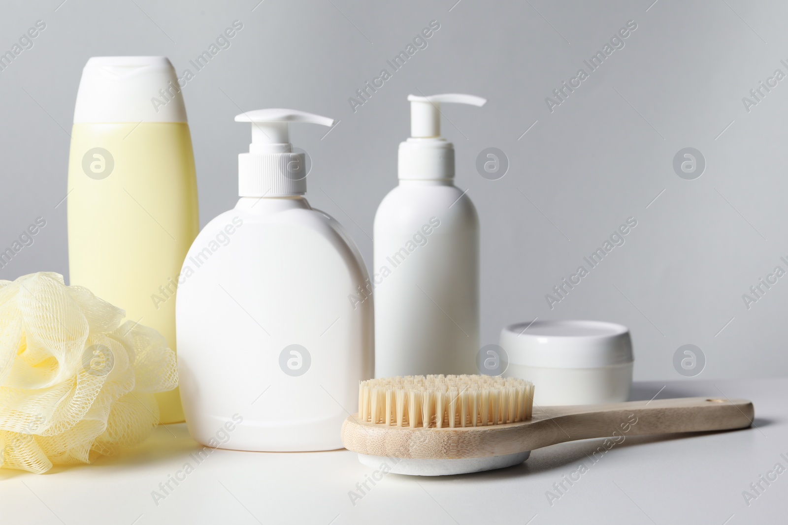 Photo of Different bath accessories on white table against grey background, closeup