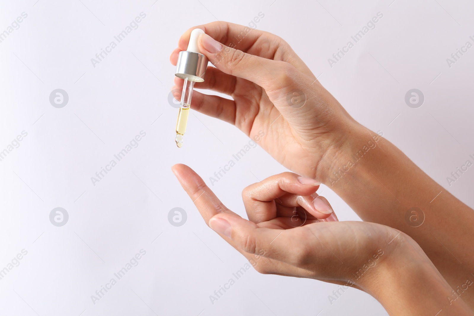 Photo of Woman applying cosmetic serum onto her finger on white background, closeup