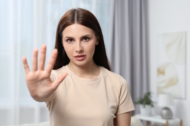 Photo of Woman showing stop gesture indoors, selective focus