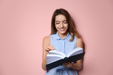 Photo of Young woman with book on color background, space for text
