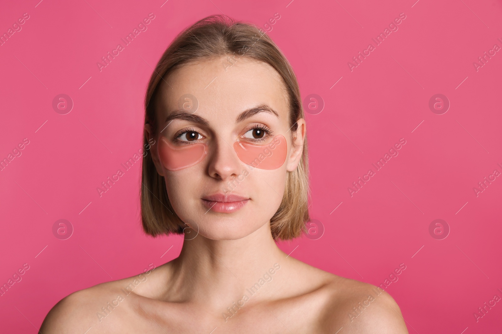 Photo of Beautiful young woman with under eye patches on pink background