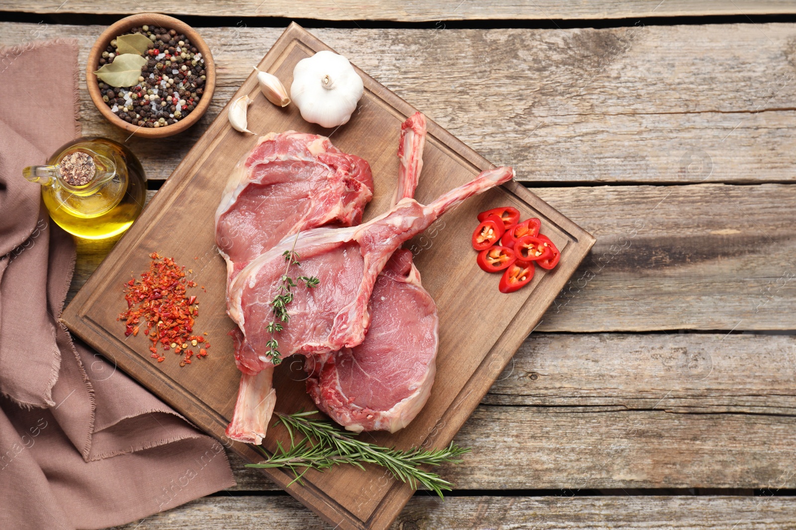 Photo of Fresh tomahawk beef cuts and spices on wooden table, top view. Space for text