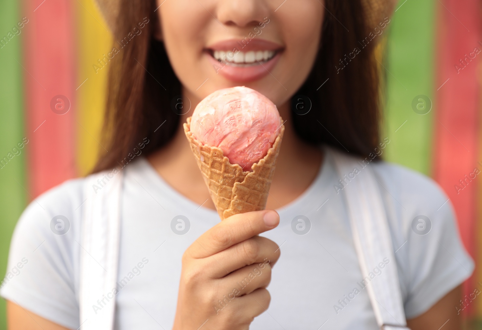 Photo of Happy young woman with delicious ice cream in waffle cone outdoors, closeup