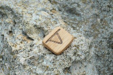 Wooden rune Thurisaz on stone outdoors, closeup