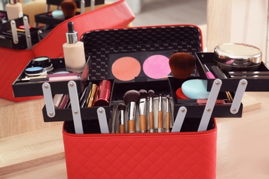 Photo of Beautician case with professional makeup products and tools on wooden dressing table