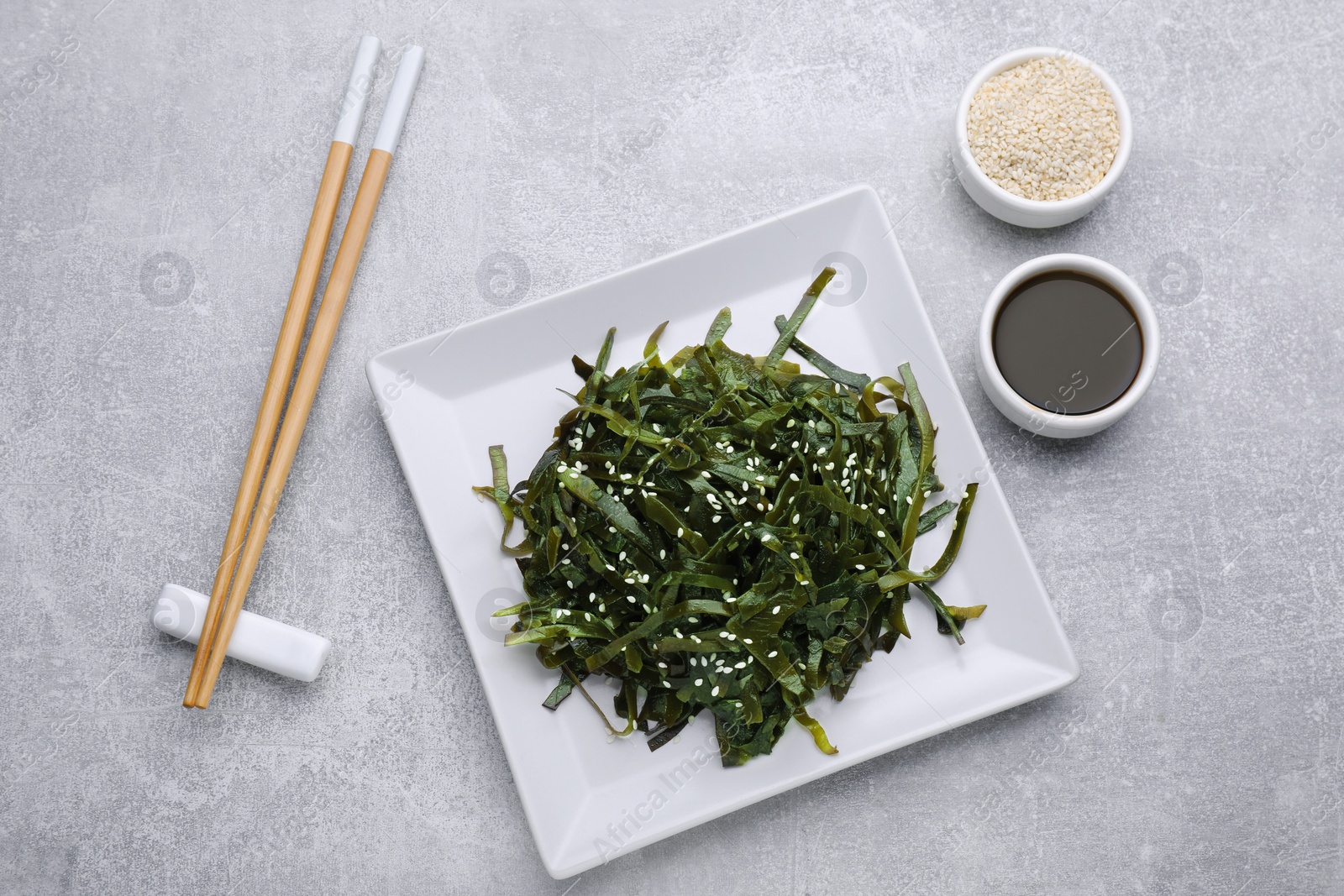 Photo of Fresh laminaria (kelp) seaweed served on light gray table, flat lay