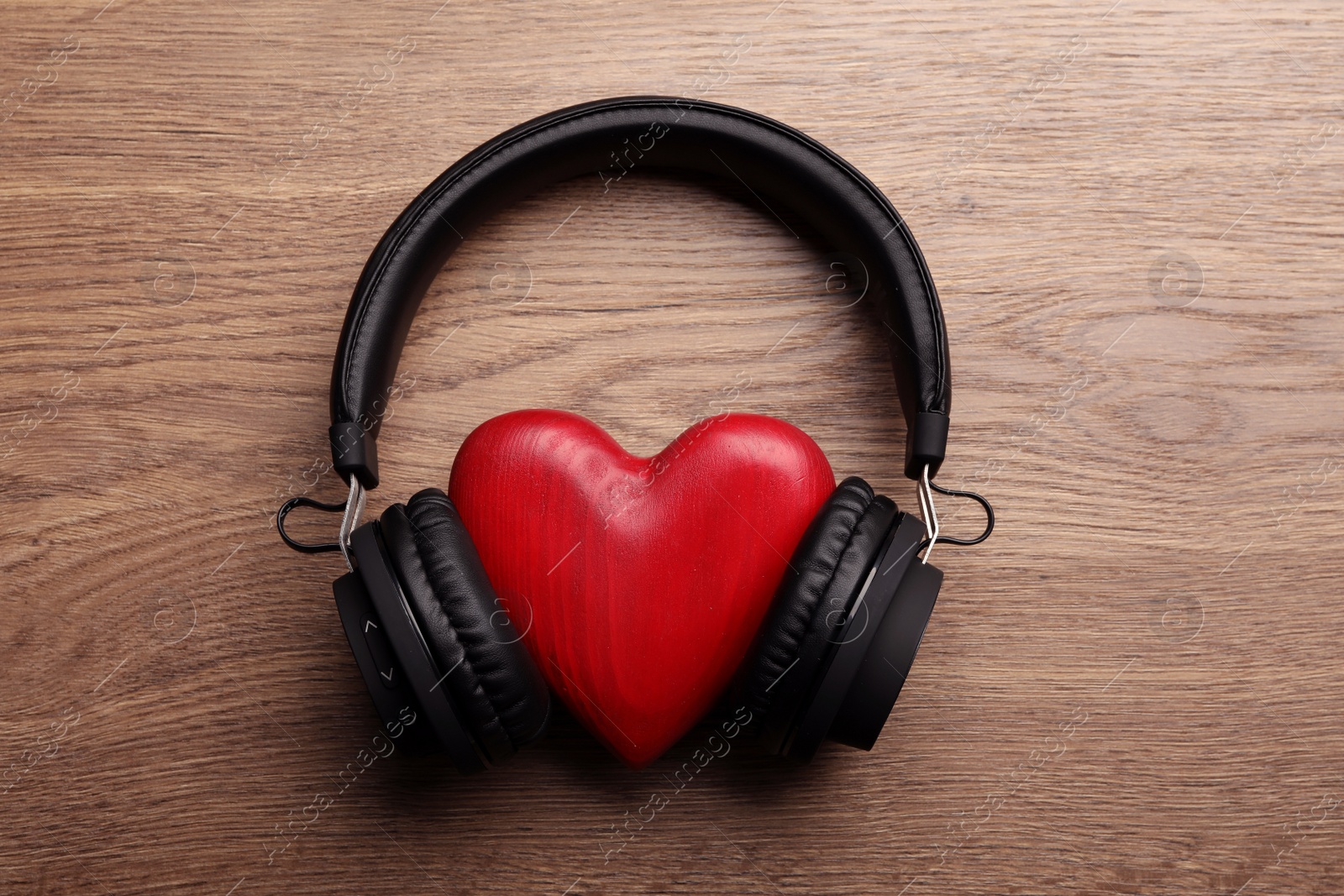 Photo of Decorative heart with modern headphones on wooden background, top view