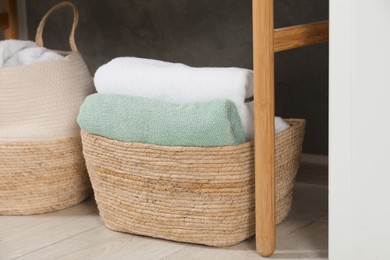 Photo of Wicker baskets with soft terry towels on floor indoors