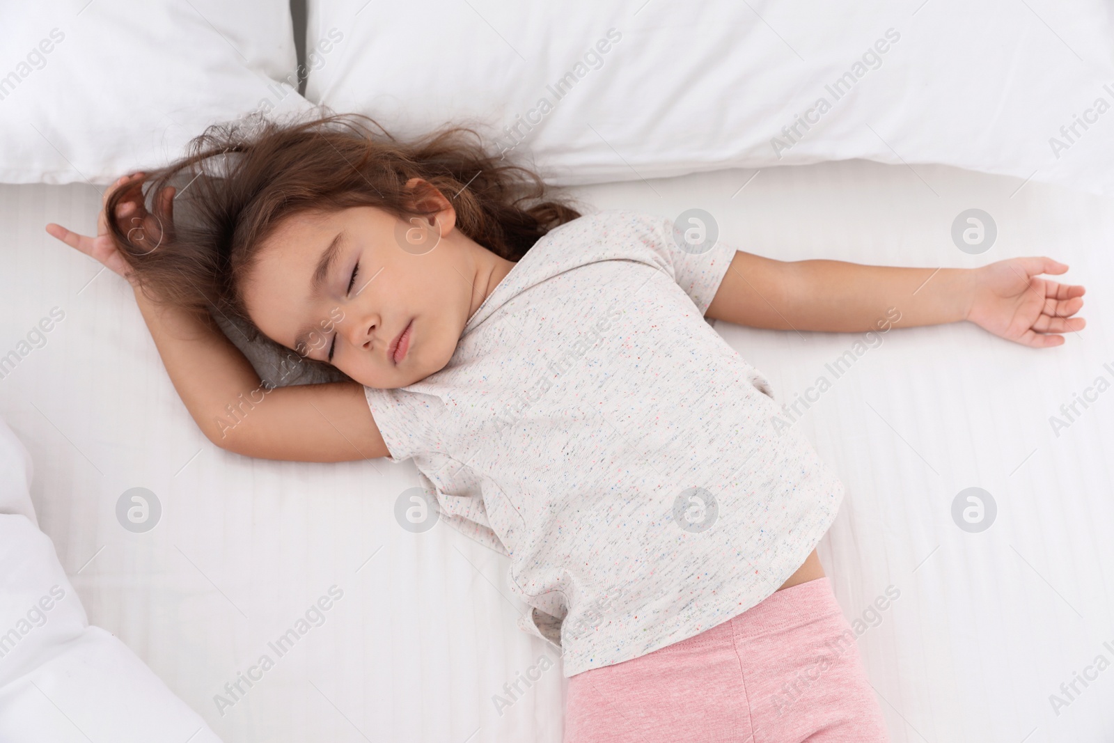 Photo of Cute little girl sleeping on cozy bed, view from above