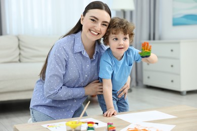 Photo of Mother and her little son painting with palms at home