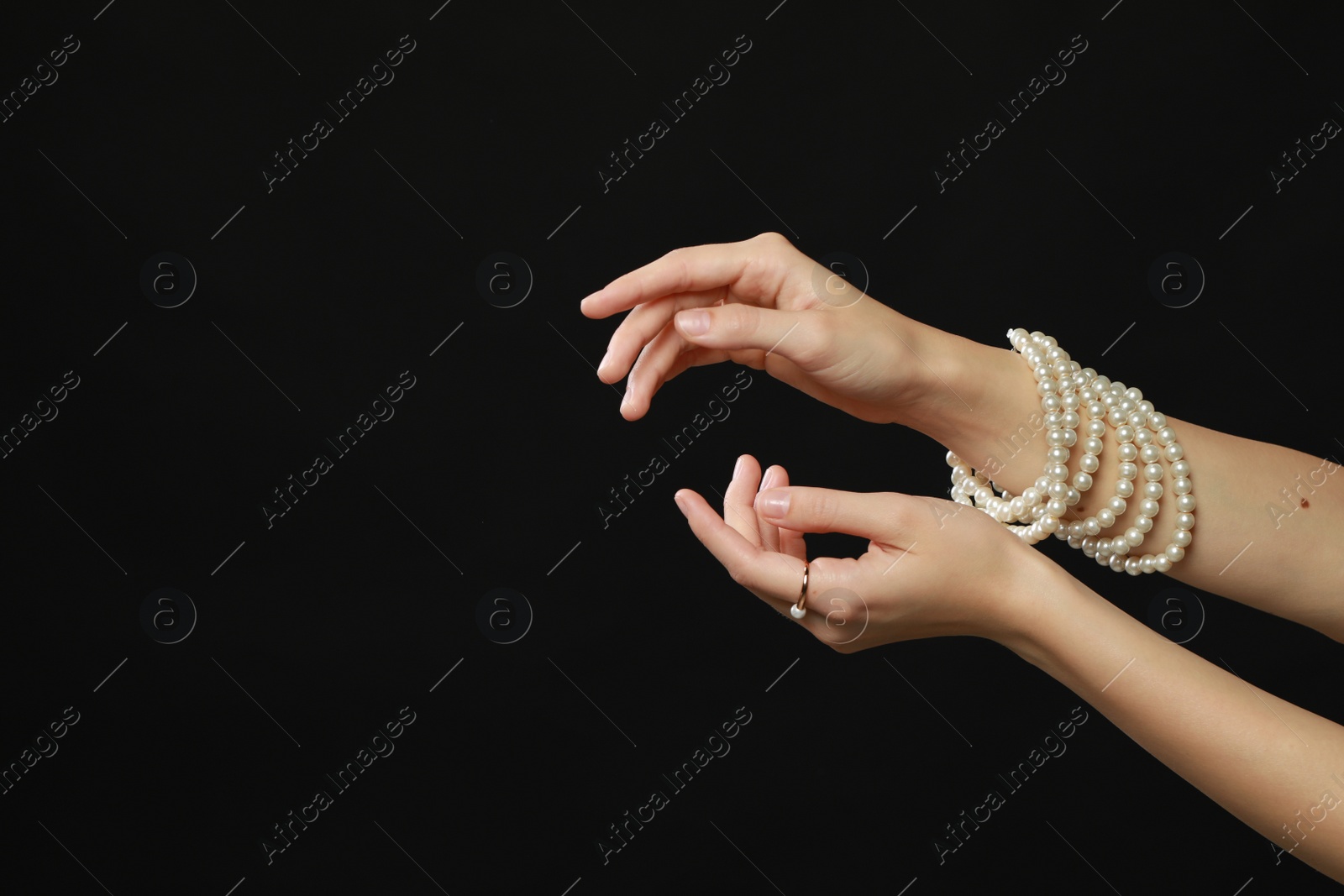 Photo of Young woman with elegant pearl jewelry on black background, closeup. Space for text