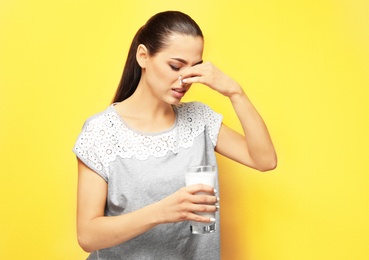 Photo of Young woman with dairy allergy holding glass of milk on color background