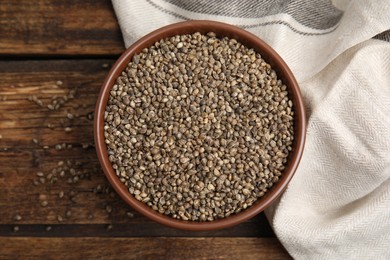 Bowl with organic hemp seeds on wooden table, flat lay