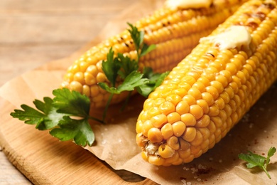 Photo of Tasty grilled corn on table, closeup view