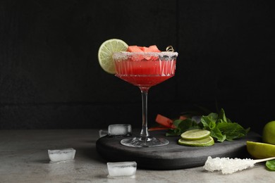 Photo of Cocktail glass of delicious fresh watermelon juice, lime, mint and ice on grey table
