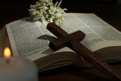 Photo of Cross, Bible, flowers and church candle on wooden table