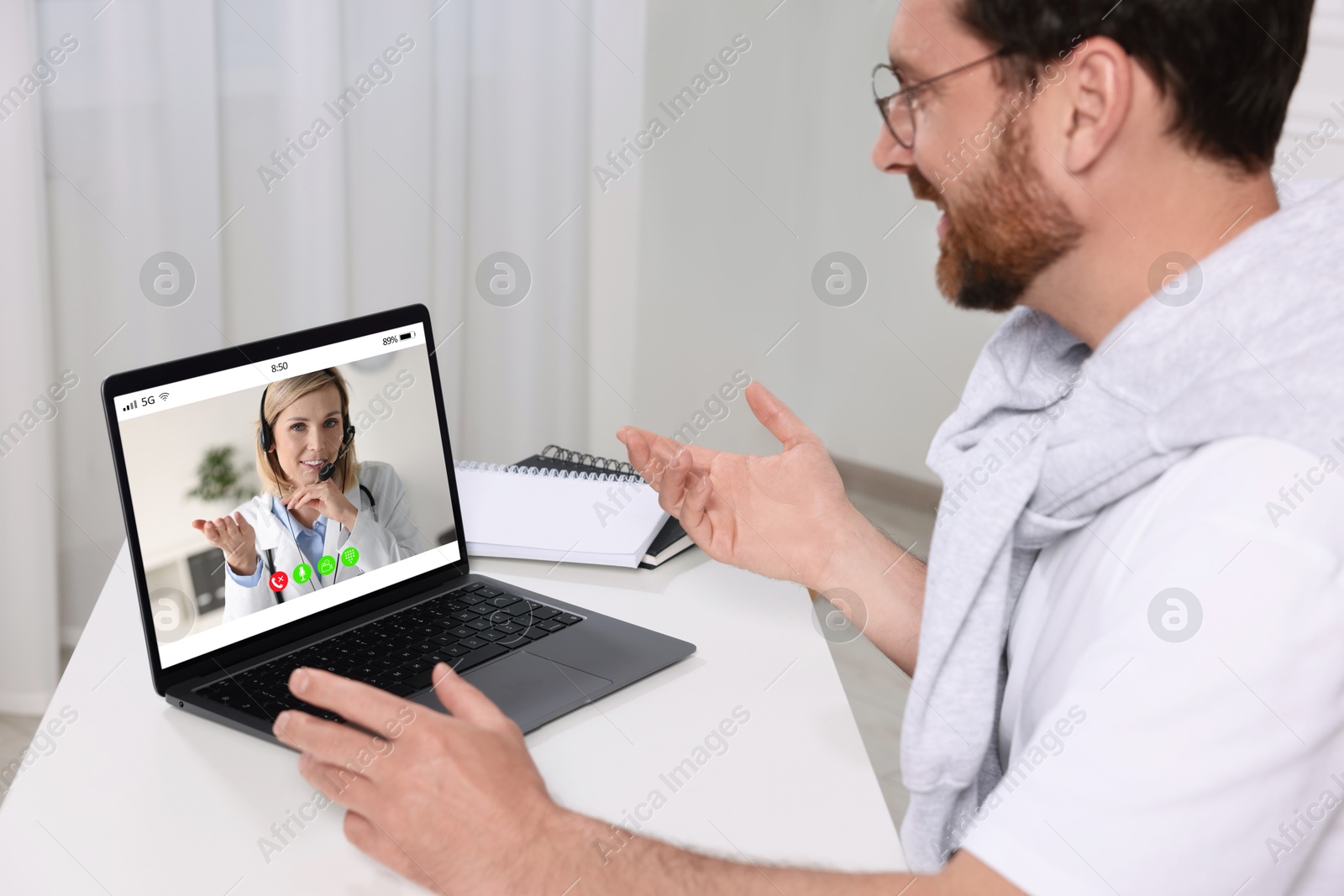 Image of Online medical consultation. Man having video chat with doctor via laptop at table indoors
