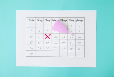 Calendar and menstrual cup on color background, top view. Gynecological care