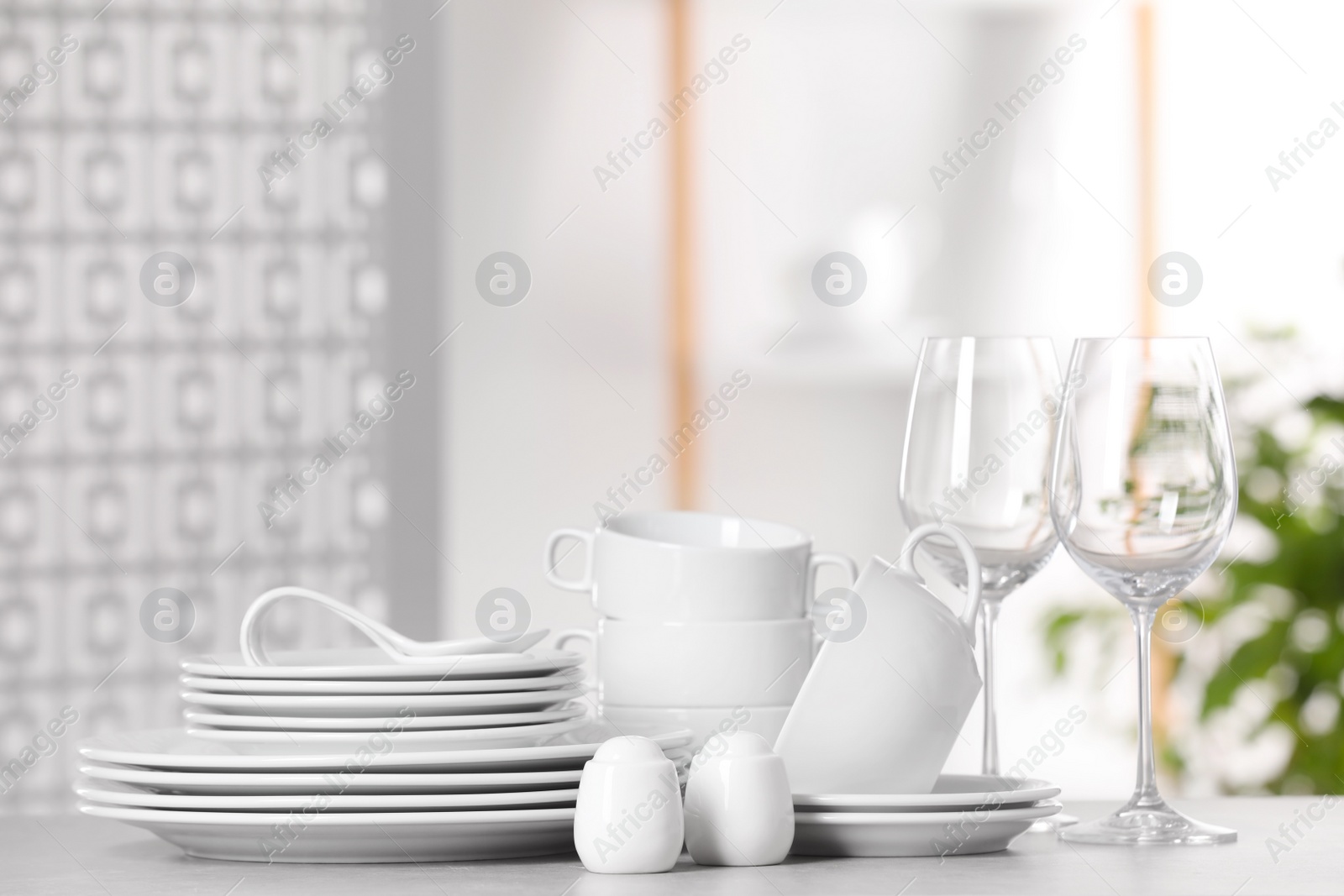 Photo of Set of clean dishware and glasses on light grey table, space for text