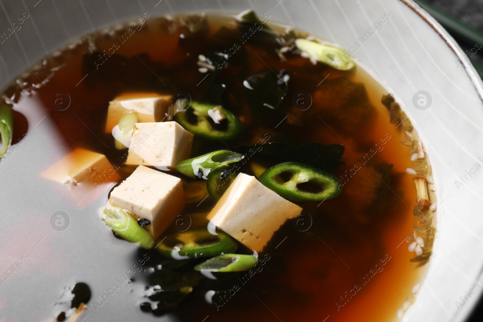 Photo of Bowl of delicious miso soup with tofu, closeup