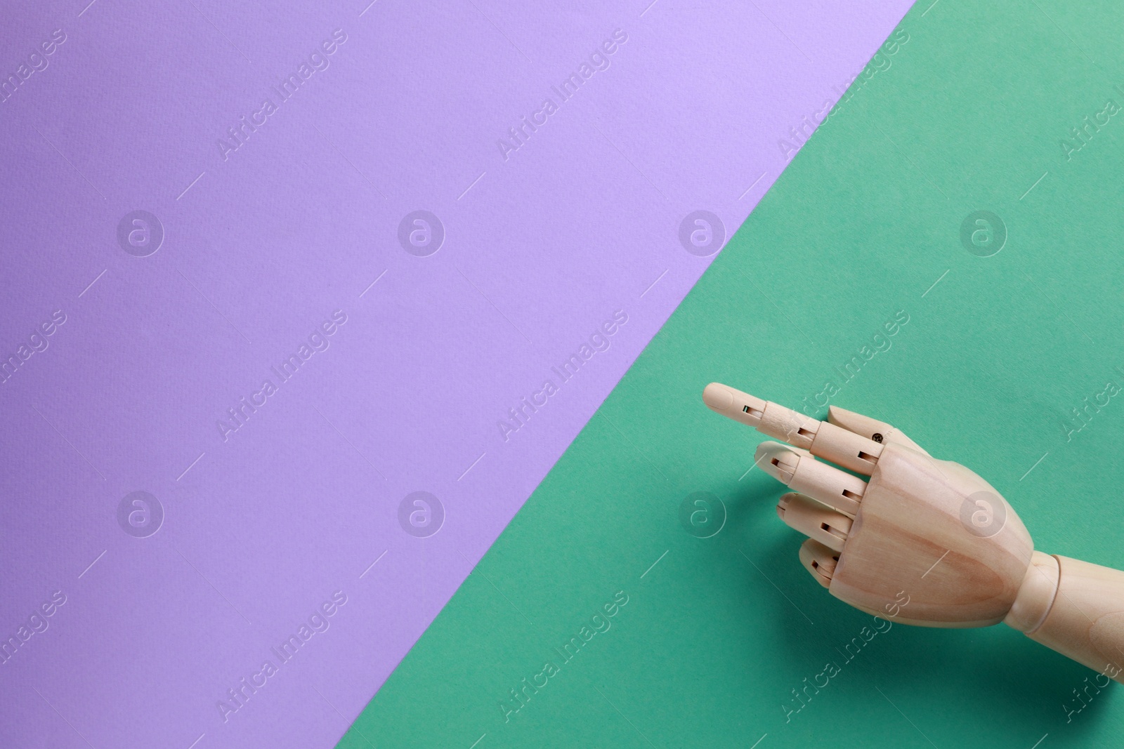 Photo of Wooden mannequin hand on color background, top view. Space for text