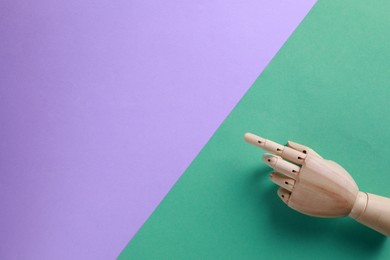 Photo of Wooden mannequin hand on color background, top view. Space for text