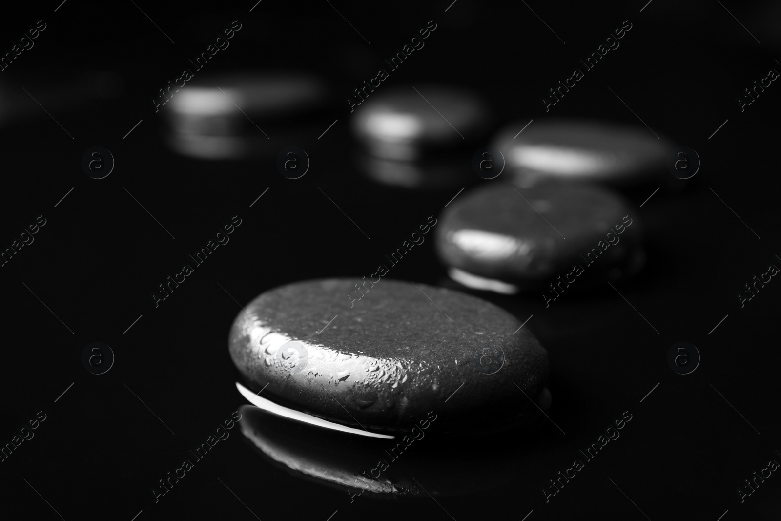 Photo of Wet spa stones on black background. Space for text