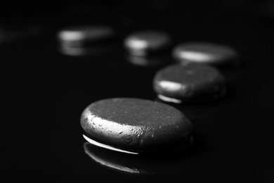 Photo of Wet spa stones on black background. Space for text