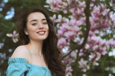 Beautiful woman near blossoming magnolia tree on spring day