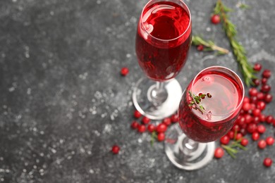 Photo of Tasty cranberry cocktail with rosemary in glasses on gray table, above view. Space for text