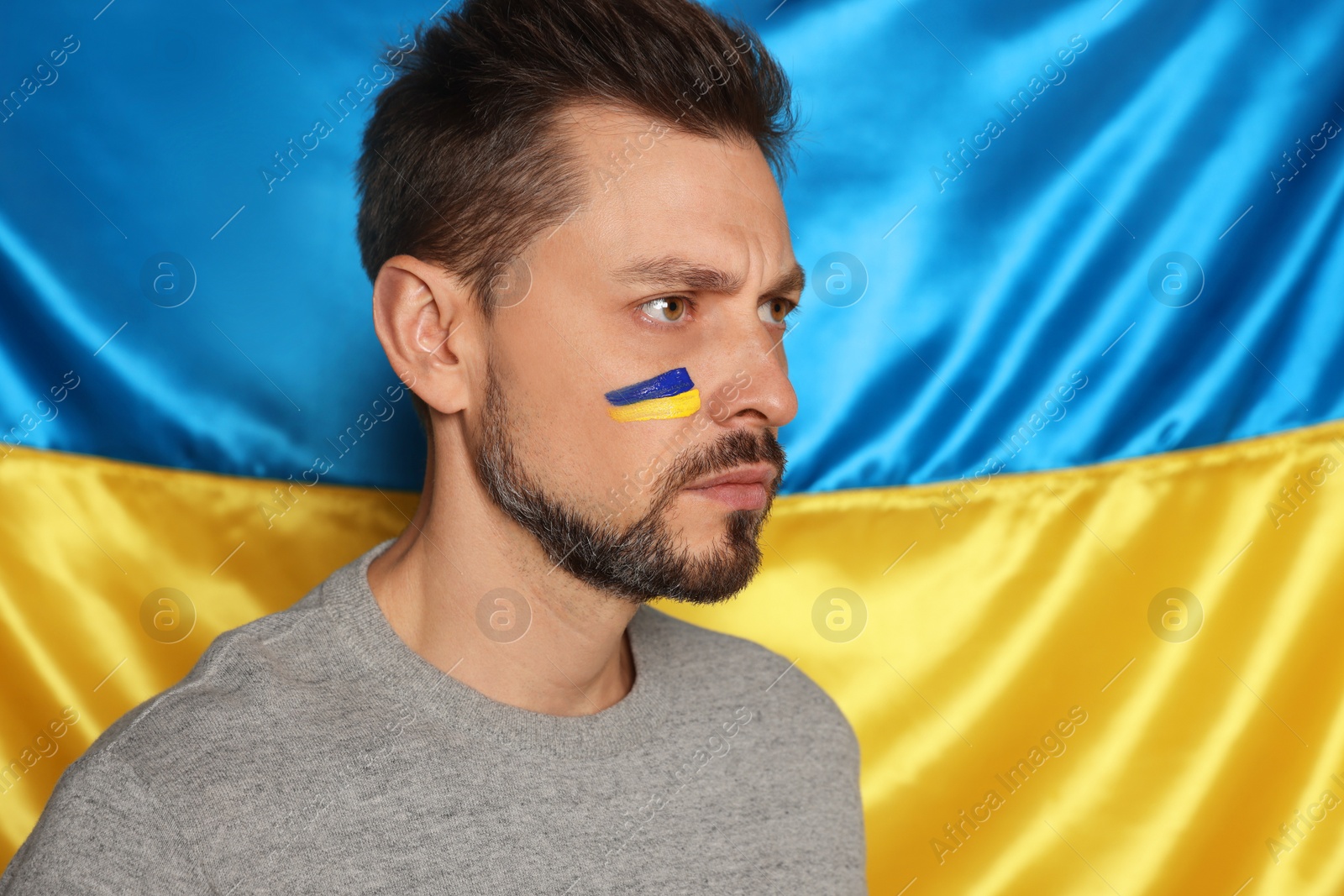 Photo of Man with face paint near Ukrainian flag