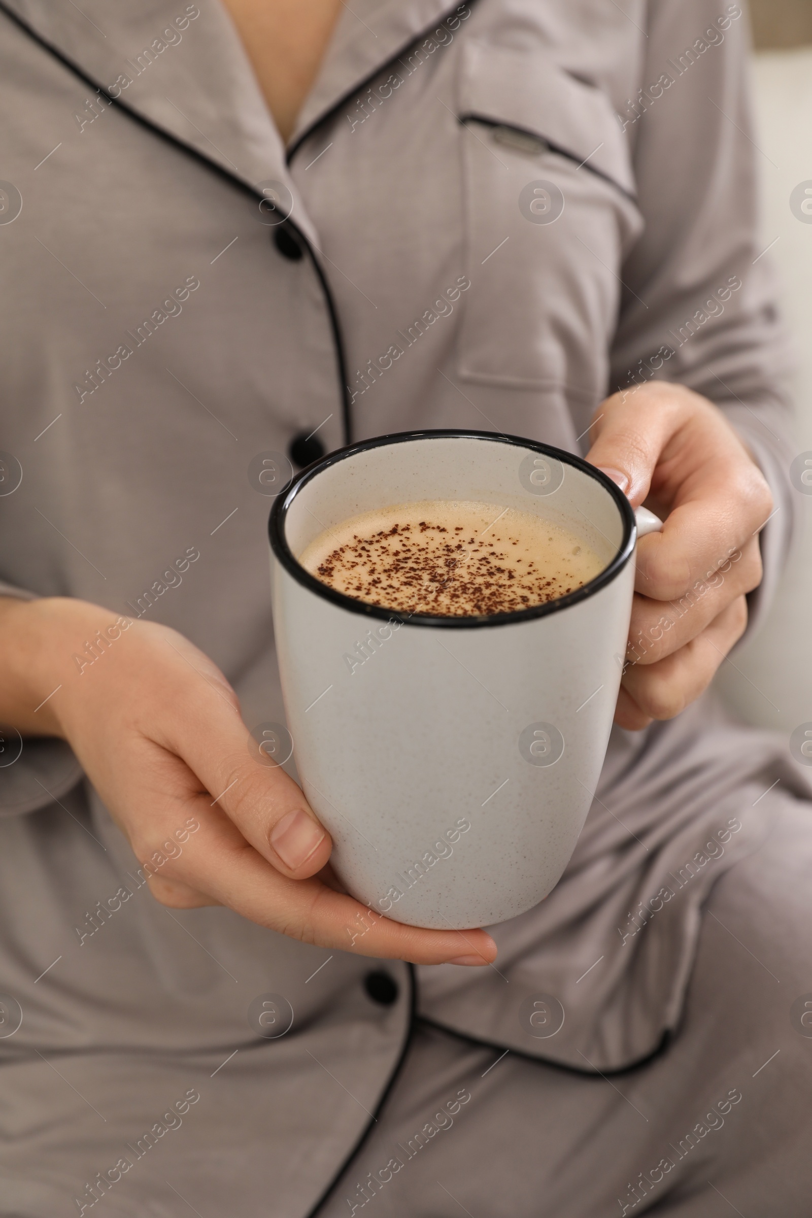 Photo of Woman in grey pajama holding cup of coffee, closeup