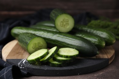 Photo of Fresh whole and cut cucumbers on table, closeup