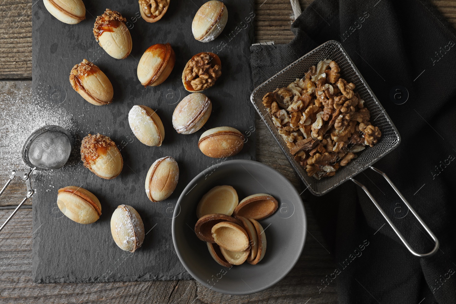 Photo of Freshly baked homemade walnut shaped cookies, flour and nuts on wooden table, flat lay
