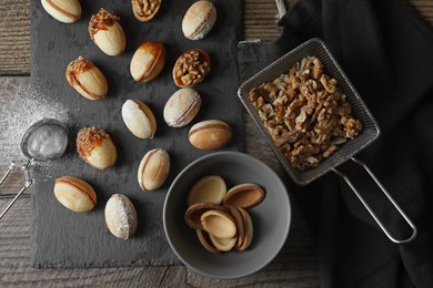 Freshly baked homemade walnut shaped cookies, flour and nuts on wooden table, flat lay